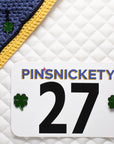 pinsnickety clover charm on a bonnet beside clover horse show number pins on a saddle pad