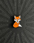 A single fox horse show number pin on a black background