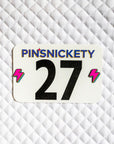 Pinsnickety Lightning Bolt horse show number pins on a saddle pad.